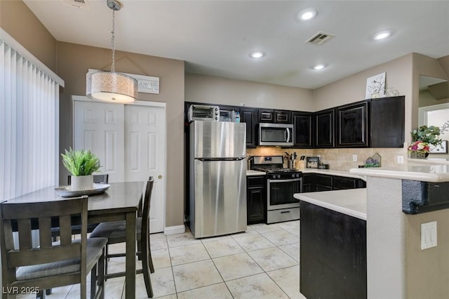 5509 Ante Up Ct Unit 102, Las Vegas, NV 89122 - kitchen featuring stainless steel appliances, dark cabinetry, tasteful backsplash, light countertops, and decorative light fixtures