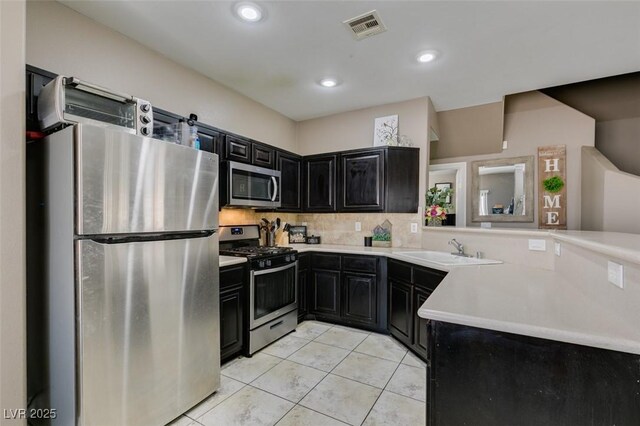 5509 Ante Up Ct Unit 102, Las Vegas, NV 89122 - kitchen with appliances with stainless steel finishes, dark cabinets, a sink, light tile patterned floors, and light countertops