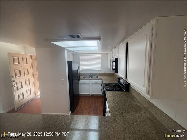 kitchen with a sink, black appliances, white cabinetry, baseboards, and dark wood-style floors