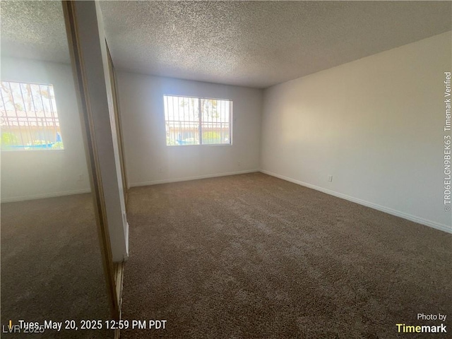 empty room featuring carpet, a textured ceiling, and baseboards