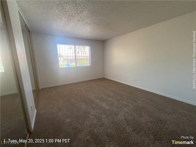 carpeted empty room featuring a textured ceiling and baseboards