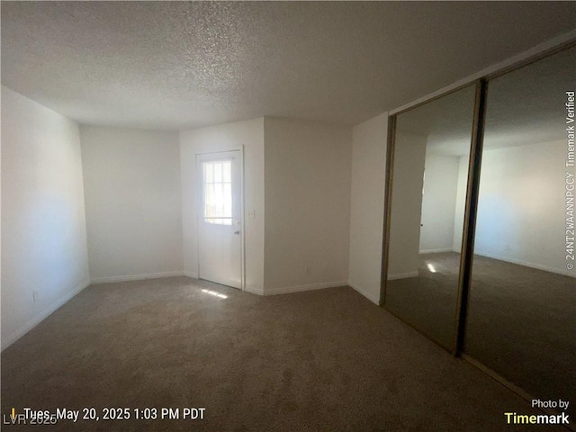 unfurnished bedroom featuring carpet flooring, a textured ceiling, a closet, and baseboards