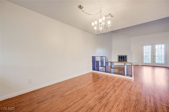1850 Camino Verde Ln, Las Vegas, NV 89119 - unfurnished living room featuring wood finished floors, a chandelier, a textured ceiling, a fireplace, and french doors