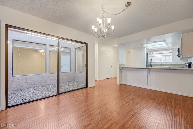 1850 Camino Verde Ln, Las Vegas, NV 89119 - unfurnished living room with light wood-type flooring, a chandelier, and a textured ceiling