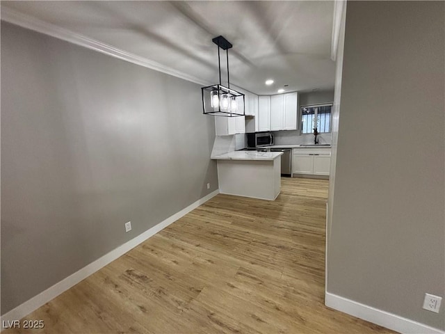 150 Greenbriar Townhouse Way, Las Vegas, NV 89121 - kitchen featuring stainless steel appliances, white cabinetry, ornamental molding, baseboards, and a peninsula