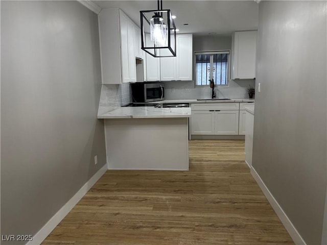 150 Greenbriar Townhouse Way, Las Vegas, NV 89121 - kitchen with stainless steel microwave, white cabinetry, decorative backsplash, baseboards, and a sink
