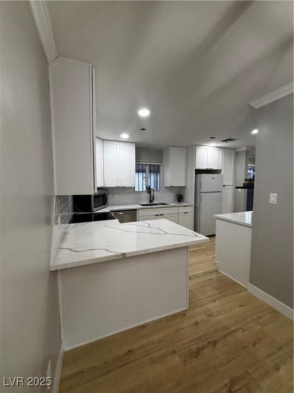150 Greenbriar Townhouse Way, Las Vegas, NV 89121 - kitchen featuring appliances with stainless steel finishes, light stone counters, white cabinets, a peninsula, and baseboards