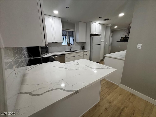 150 Greenbriar Townhouse Way, Las Vegas, NV 89121 - kitchen featuring stainless steel appliances, a sink, light stone countertops, light wood finished floors, and recessed lighting