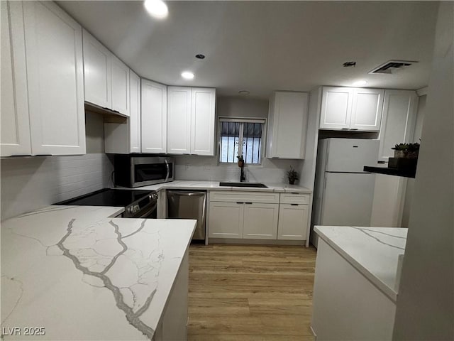 150 Greenbriar Townhouse Way, Las Vegas, NV 89121 - kitchen featuring a sink, stainless steel appliances, light wood-type flooring, light stone counters, and recessed lighting