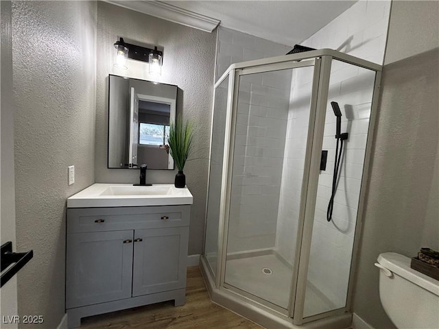 150 Greenbriar Townhouse Way, Las Vegas, NV 89121 - full bathroom featuring a textured wall, a shower stall, wood finished floors, toilet, and vanity