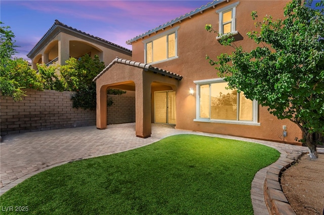 11847 Corenzio Ave, Las Vegas, NV 89138 - back of property at dusk with a patio, a tiled roof, a yard, and stucco siding