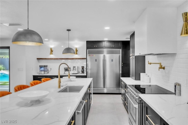 3189 Montecito Dr, Las Vegas, NV 89120 - kitchen featuring appliances with stainless steel finishes, decorative backsplash, light stone counters, hanging light fixtures, and a sink