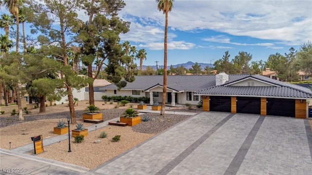 3189 Montecito Dr, Las Vegas, NV 89120 - ranch-style home with a tiled roof, a mountain view, a chimney, a garage, and decorative driveway