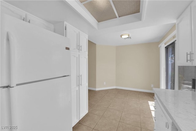 542 Grimsby Ave, Henderson, NV 89014 - kitchen with freestanding refrigerator, white cabinetry, a tray ceiling, light tile patterned floors, and baseboards