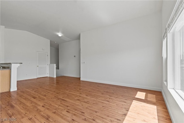 2596 Lazy Saddle Dr, Henderson, NV 89002 - unfurnished living room with light wood-type flooring, vaulted ceiling, healthy amount of natural light, and baseboards