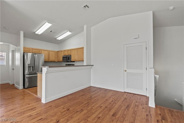 2596 Lazy Saddle Dr, Henderson, NV 89002 - kitchen featuring stainless steel appliances, vaulted ceiling, light wood-style flooring, arched walkways, and a peninsula