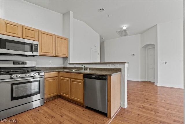 2596 Lazy Saddle Dr, Henderson, NV 89002 - kitchen with stainless steel appliances, a sink, light wood-type flooring, a peninsula, and dark countertops