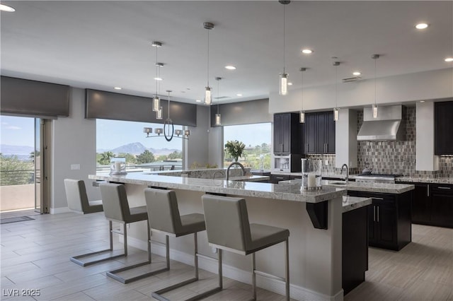 1683 Tangiers Dr, Henderson, NV 89012 - kitchen with a spacious island, wall chimney exhaust hood, backsplash, a kitchen bar, and recessed lighting