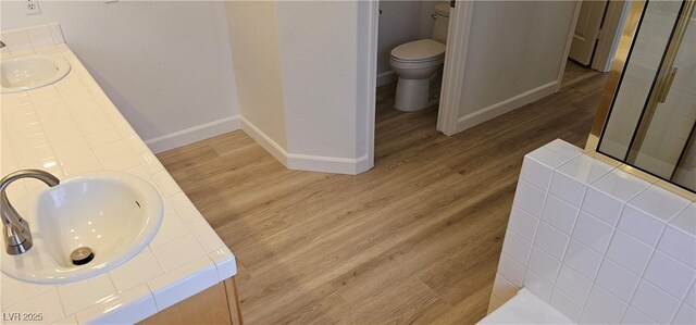 3750 Morning Canyon St, Las Vegas, NV 89147 - bathroom featuring a stall shower, double vanity, toilet, baseboards, and wood finished floors