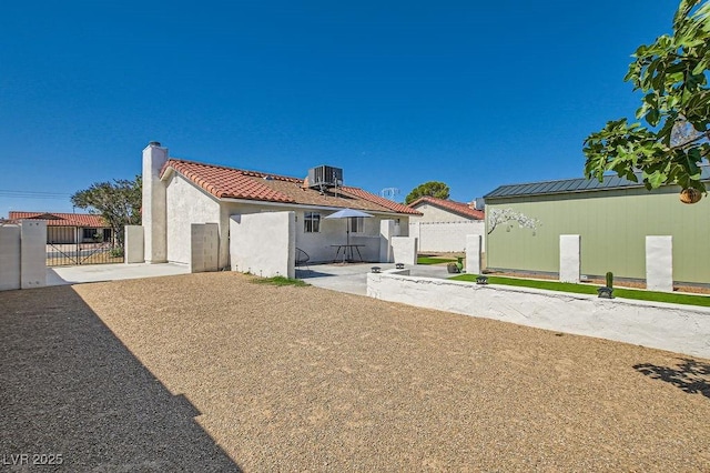 445 Concord Way, Henderson, NV 89015 - rear view of property featuring a gate, central AC, a chimney, stucco siding, and a tiled roof