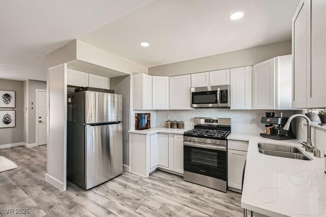 445 Concord Way, Henderson, NV 89015 - kitchen with appliances with stainless steel finishes, a sink, light stone countertops, light wood-type flooring, and white cabinetry