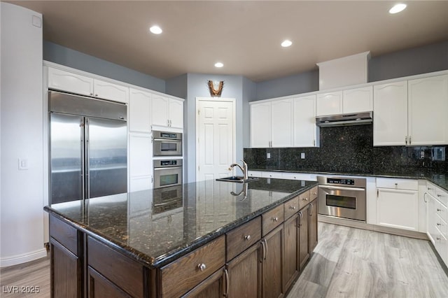 5210 Villa Dante Ave, Las Vegas, NV 89141 - kitchen with under cabinet range hood, light wood-style flooring, white cabinets, a sink, and recessed lighting