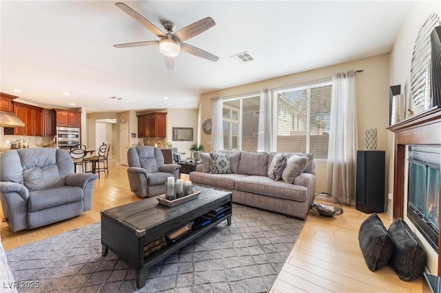7567 Desertscape Ave, Las Vegas, NV 89178 - living room with light wood-style flooring, a ceiling fan, recessed lighting, and a glass covered fireplace