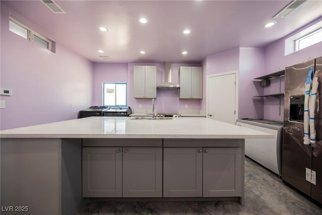 2807 Hermosa St, Las Vegas, NV 89169 - kitchen featuring washing machine and dryer, stainless steel refrigerator with ice dispenser, wall chimney exhaust hood, gray cabinetry, and recessed lighting