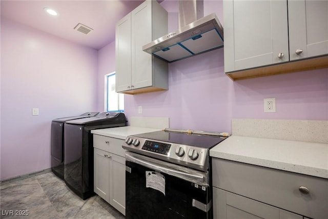 2807 Hermosa St, Las Vegas, NV 89169 - kitchen with stainless steel range with electric stovetop, wall chimney exhaust hood, separate washer and dryer, light countertops, and recessed lighting