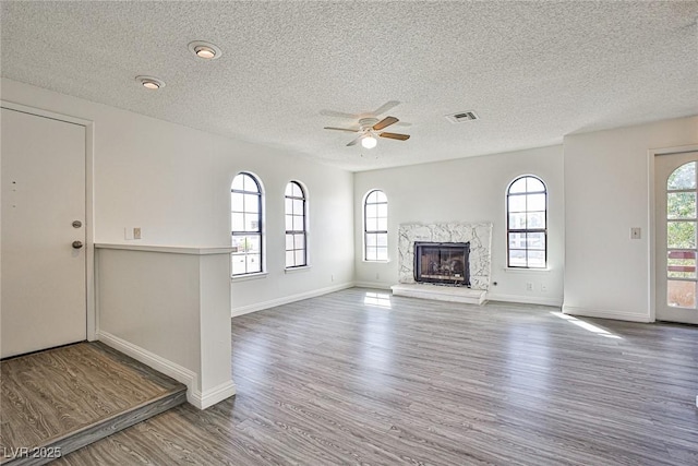 4083 Nook Way Unit D, Las Vegas, NV 89103 - unfurnished living room featuring a textured ceiling, a ceiling fan, wood finished floors, a high end fireplace, and baseboards