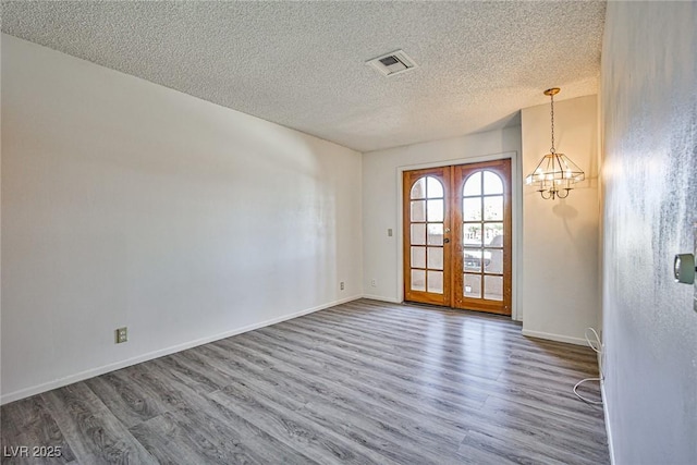 4083 Nook Way Unit D, Las Vegas, NV 89103 - empty room with wood finished floors, a textured ceiling, a chandelier, french doors, and baseboards