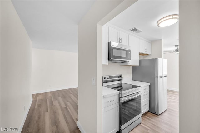 1832 N Decatur Blvd Unit 104, Las Vegas, NV 89108 - kitchen with stainless steel appliances, light wood finished floors, white cabinetry, and light countertops