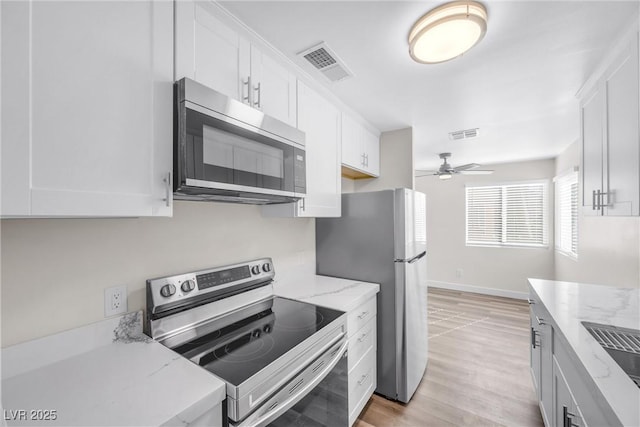 1832 N Decatur Blvd Unit 104, Las Vegas, NV 89108 - kitchen with stainless steel appliances, white cabinetry, ceiling fan, light wood-type flooring, and light stone counters