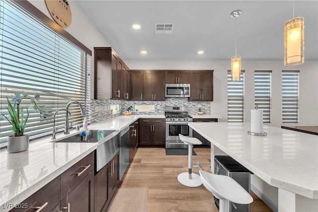 8076 Haywood Estate Ave, Las Vegas, NV 89113 - kitchen with stainless steel appliances, a kitchen bar, plenty of natural light, dark brown cabinetry, and recessed lighting