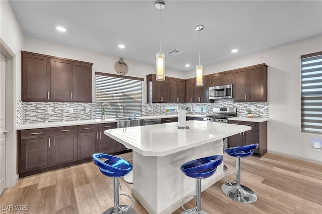 8076 Haywood Estate Ave, Las Vegas, NV 89113 - kitchen featuring appliances with stainless steel finishes, a breakfast bar area, a sink, light wood-type flooring, and dark brown cabinets