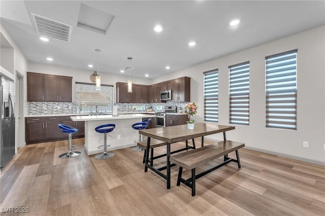 8076 Haywood Estate Ave, Las Vegas, NV 89113 - kitchen featuring appliances with stainless steel finishes, dark brown cabinetry, a center island, a kitchen bar, and recessed lighting