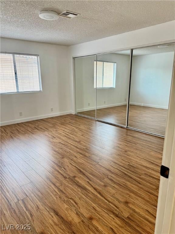 1320 Driscoll Dr Unit 202, Las Vegas, NV 89128 - unfurnished bedroom featuring a textured ceiling, wood finished floors, baseboards, and a closet