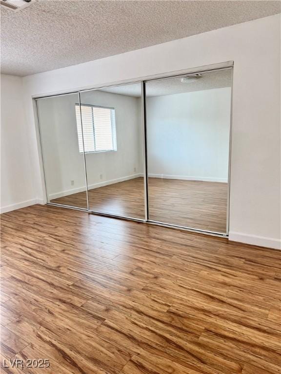 1320 Driscoll Dr Unit 202, Las Vegas, NV 89128 - unfurnished bedroom featuring wood finished floors, a textured ceiling, baseboards, and a closet