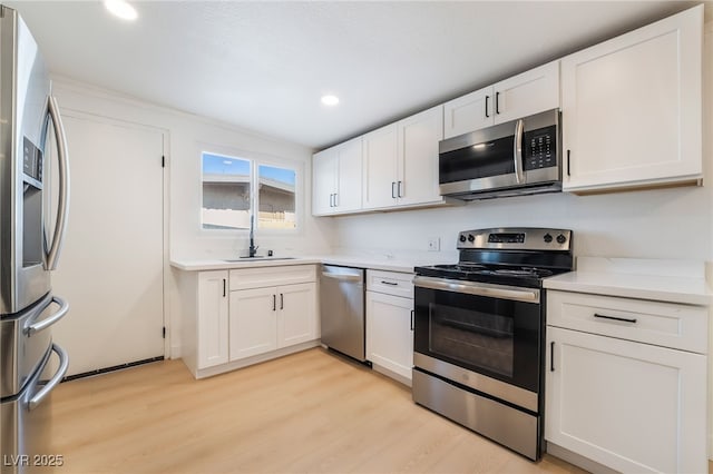 5069 Hallet Dr, Las Vegas, NV 89122 - kitchen featuring appliances with stainless steel finishes, a sink, light wood-type flooring, white cabinets, and recessed lighting