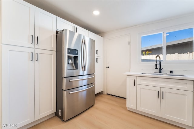 5069 Hallet Dr, Las Vegas, NV 89122 - kitchen featuring stainless steel refrigerator with ice dispenser, a sink, light wood-type flooring, light countertops, and white cabinets