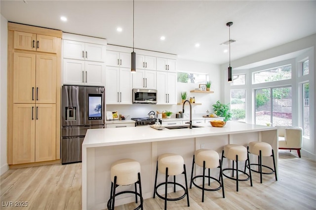 10025 Netherton Dr, Las Vegas, NV 89134 - kitchen with stainless steel appliances, a sink, a kitchen island with sink, light wood-style flooring, and recessed lighting