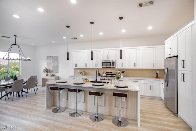 10025 Netherton Dr, Las Vegas, NV 89134 - kitchen featuring appliances with stainless steel finishes, tasteful backsplash, a breakfast bar, light wood-type flooring, and a sink