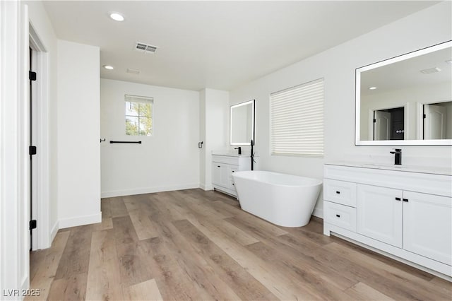 25 Blue Valley Dr, Henderson, NV 89002 - full bath with a freestanding tub, two vanities, wood finished floors, recessed lighting, and baseboards