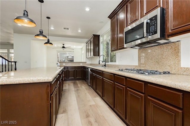 25 Blue Valley Dr, Henderson, NV 89002 - kitchen featuring appliances with stainless steel finishes, light wood-type flooring, a ceiling fan, a sink, and tasteful backsplash