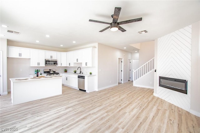 6387 Azurelyn Ave, Las Vegas, NV 89122 - kitchen with appliances with stainless steel finishes, light wood-style floors, a sink, ceiling fan, and white cabinets