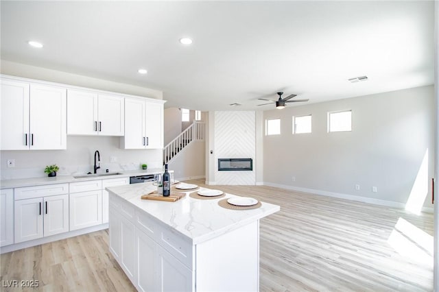 6387 Azurelyn Ave, Las Vegas, NV 89122 - kitchen with a sink, ceiling fan, a kitchen island, light wood-style floors, and white cabinets