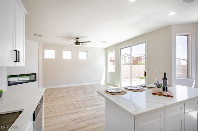 6387 Azurelyn Ave, Las Vegas, NV 89122 - kitchen with baseboards, light wood finished floors, ceiling fan, white cabinetry, and light stone countertops