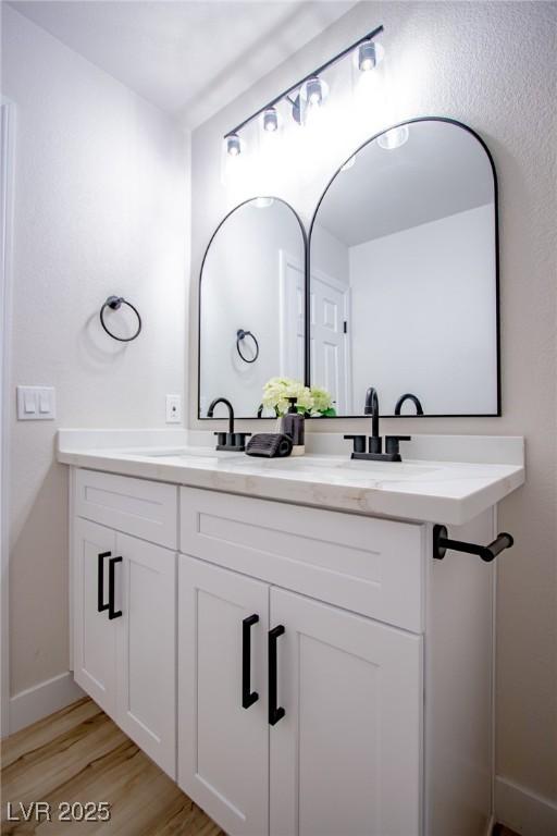 6387 Azurelyn Ave, Las Vegas, NV 89122 - bathroom featuring double vanity, wood finished floors, and baseboards