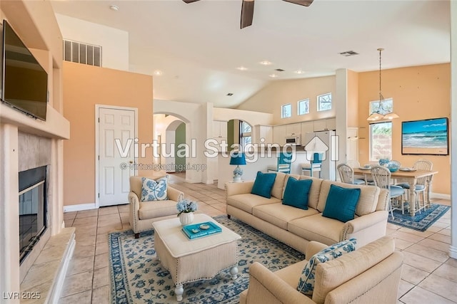 2889 Anteres St, Las Vegas, NV 89117 - living room with light tile patterned flooring, ceiling fan, high vaulted ceiling, a glass covered fireplace, and arched walkways