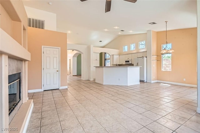 2889 Anteres St, Las Vegas, NV 89117 - unfurnished living room featuring ceiling fan, light tile patterned flooring, high vaulted ceiling, a glass covered fireplace, and arched walkways